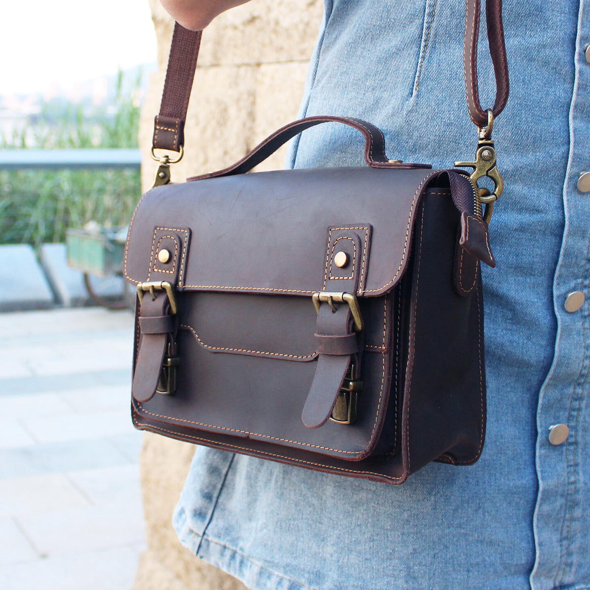 Side view of brown leather messenger satchel worn over the shoulder
