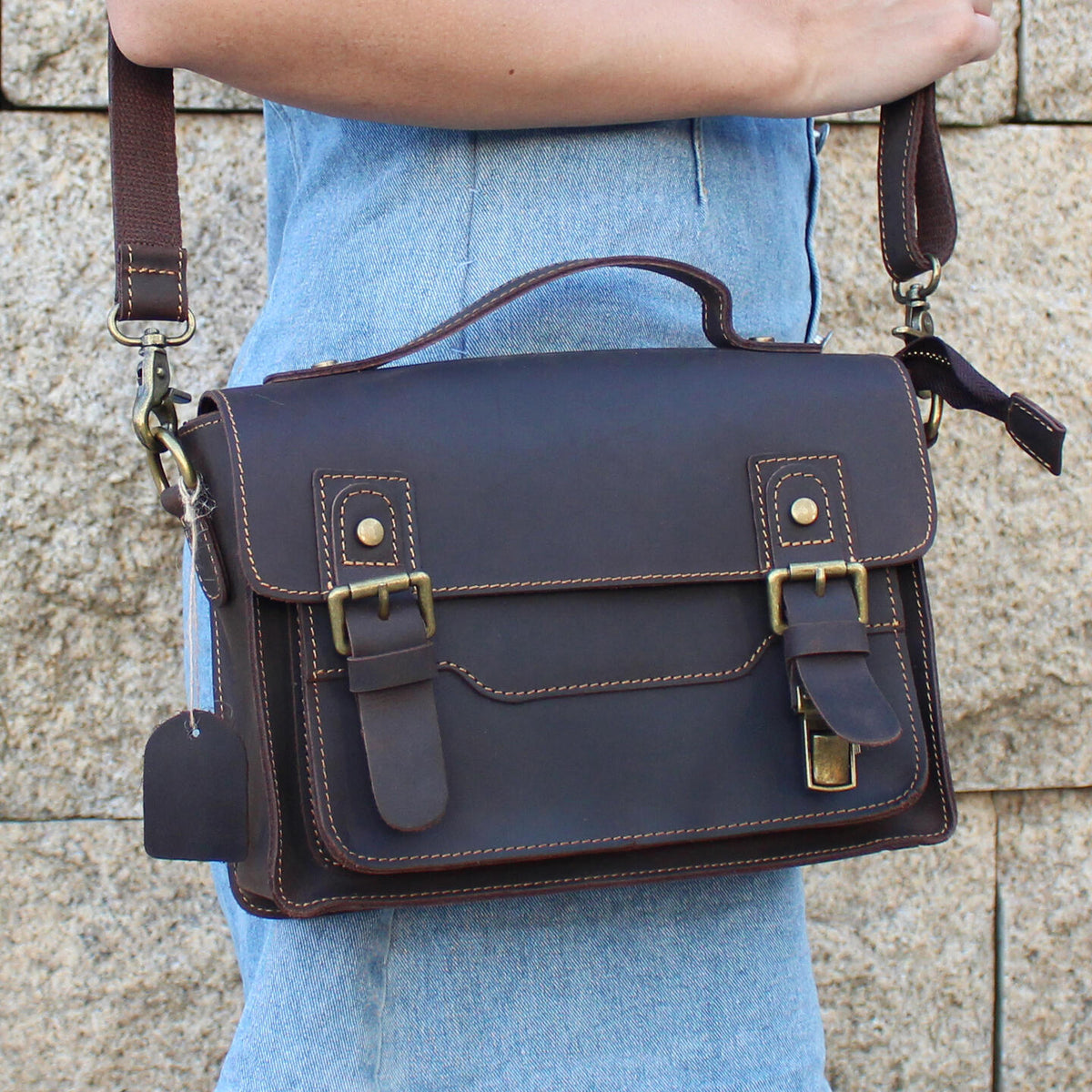 Brown leather messenger satchel worn at the hip with adjustable shoulder strap