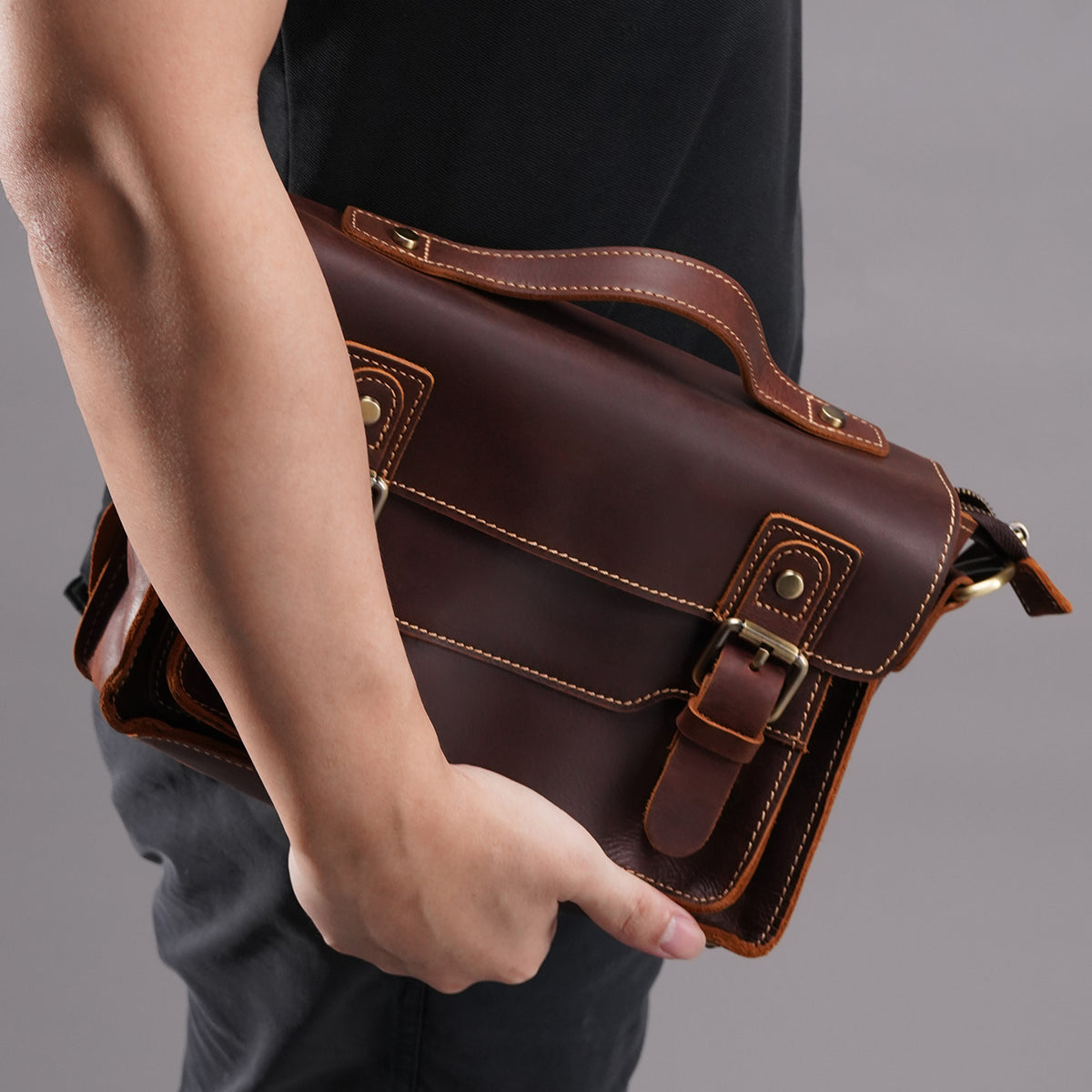 Brown crazy-horse leather messenger satchel held close against the body