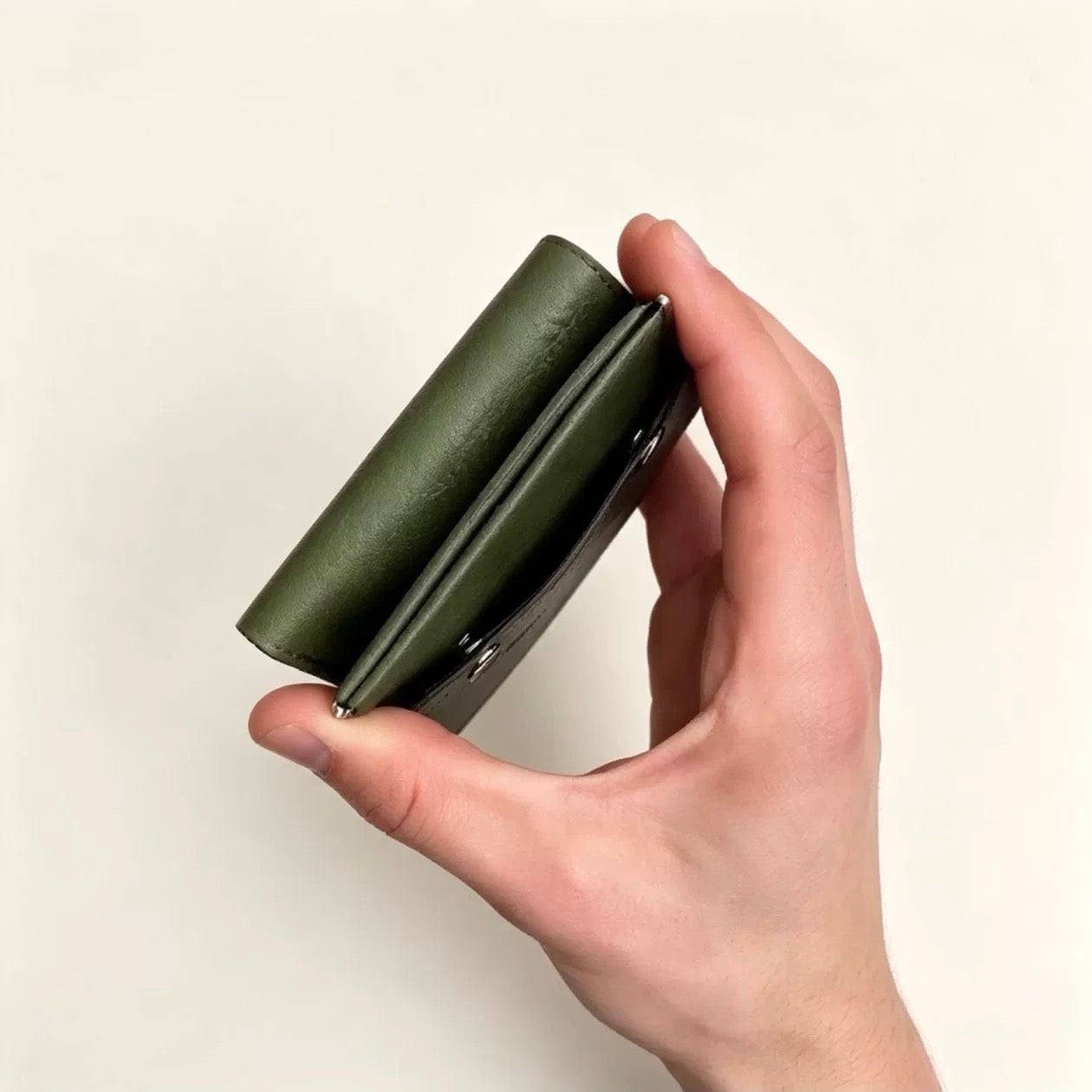 Green lightweight trifold wallet side profile held in hand