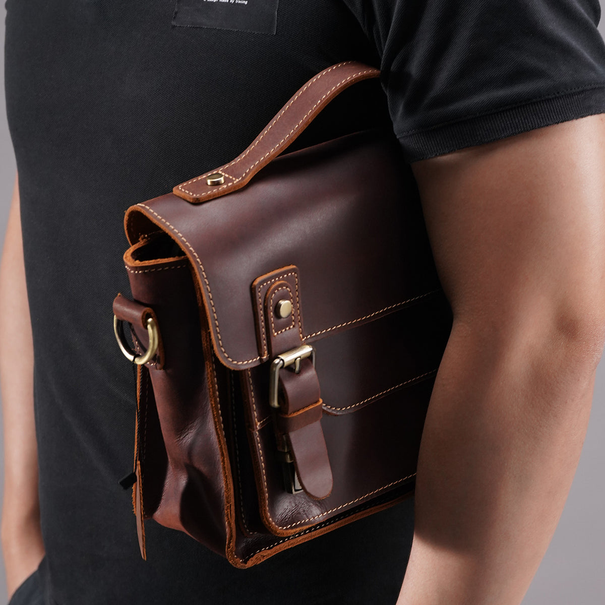 Brown leather messenger satchel tucked securely under the arm