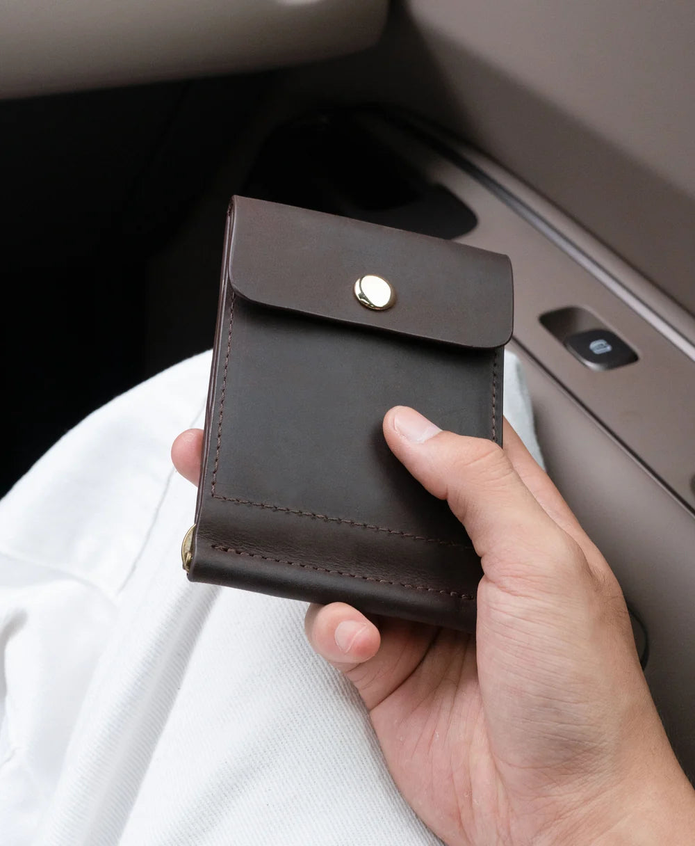Compact dark brown leather money clip wallet carried by hand