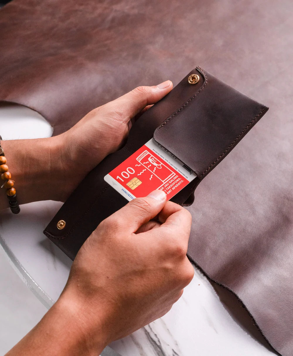 Dark brown Crazy Horse leather bifold wallet in an everyday setting