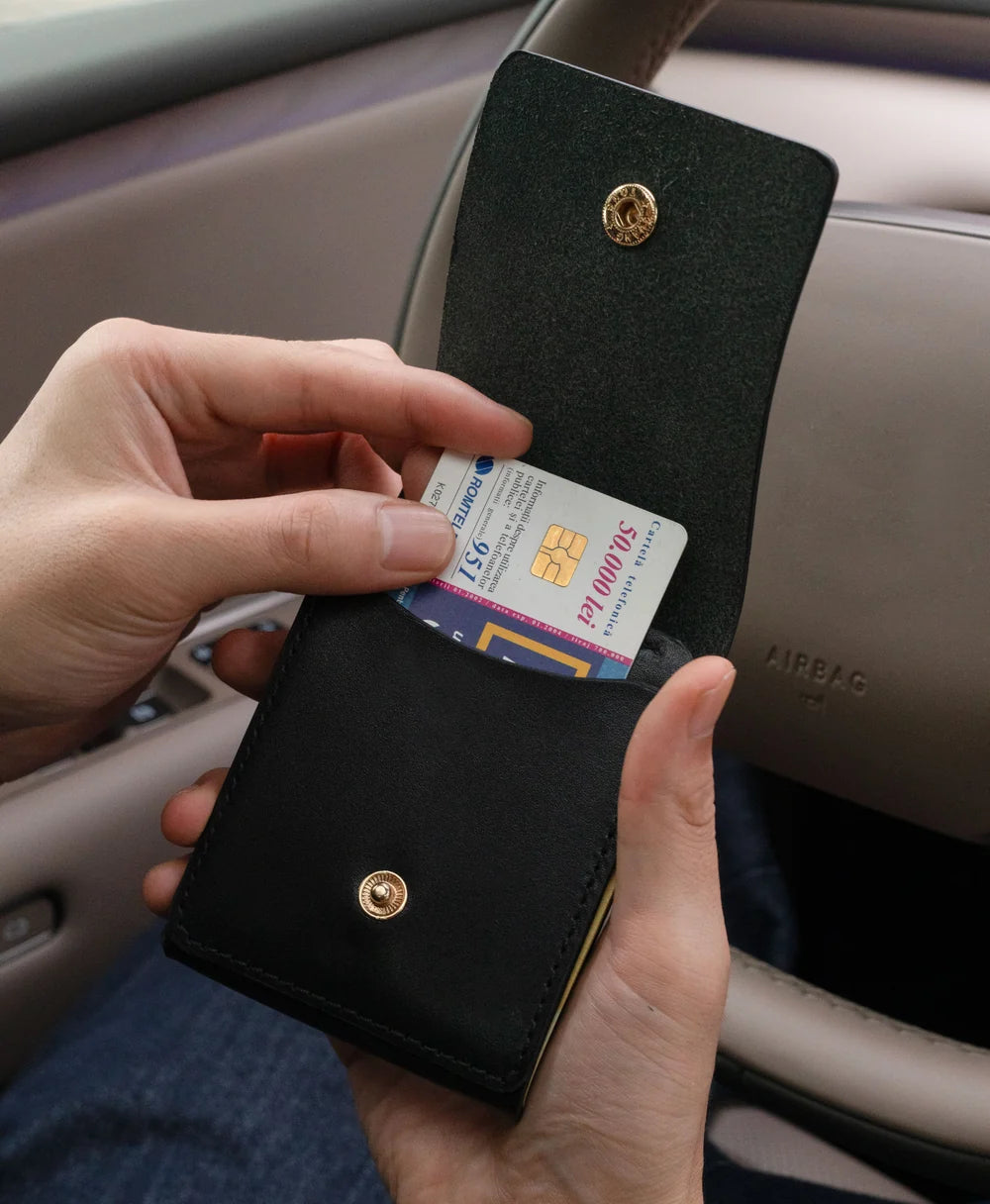Black full-grain saddle leather vertical wallet carried in an everyday setting