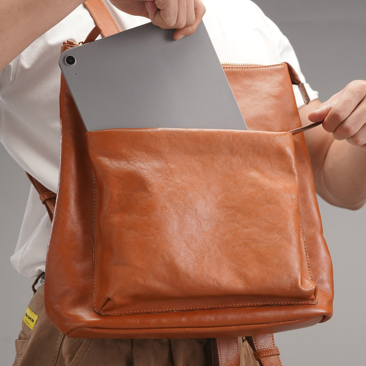 Tablet being placed into the front zip pocket of the leather backpack