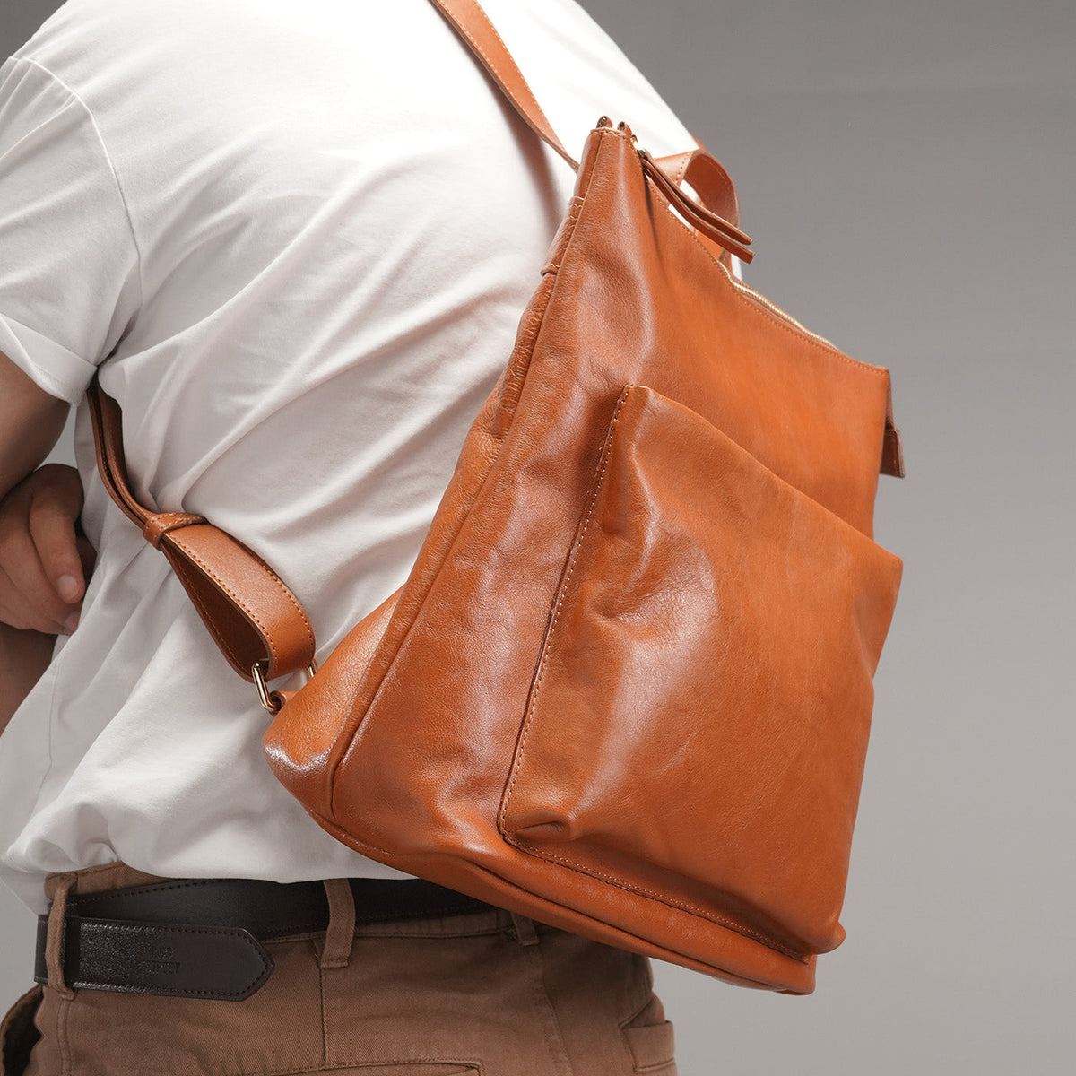 Side profile of the tan full-grain leather backpack while worn