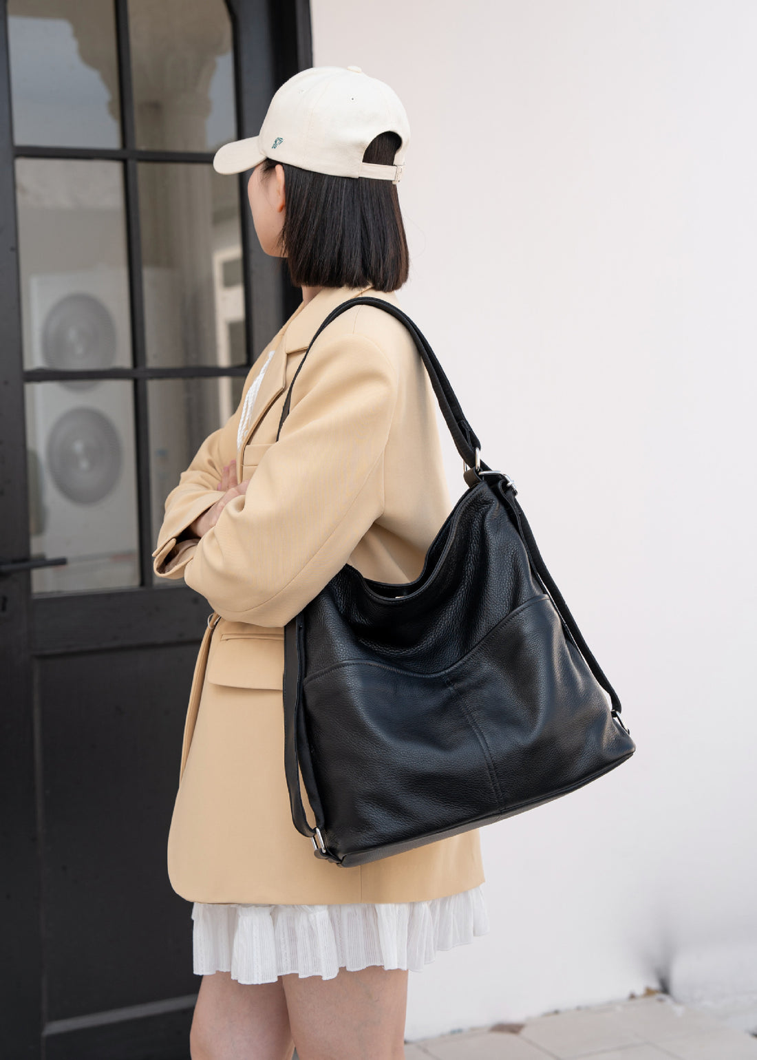 Black soft leather tote backpack carried on one shoulder