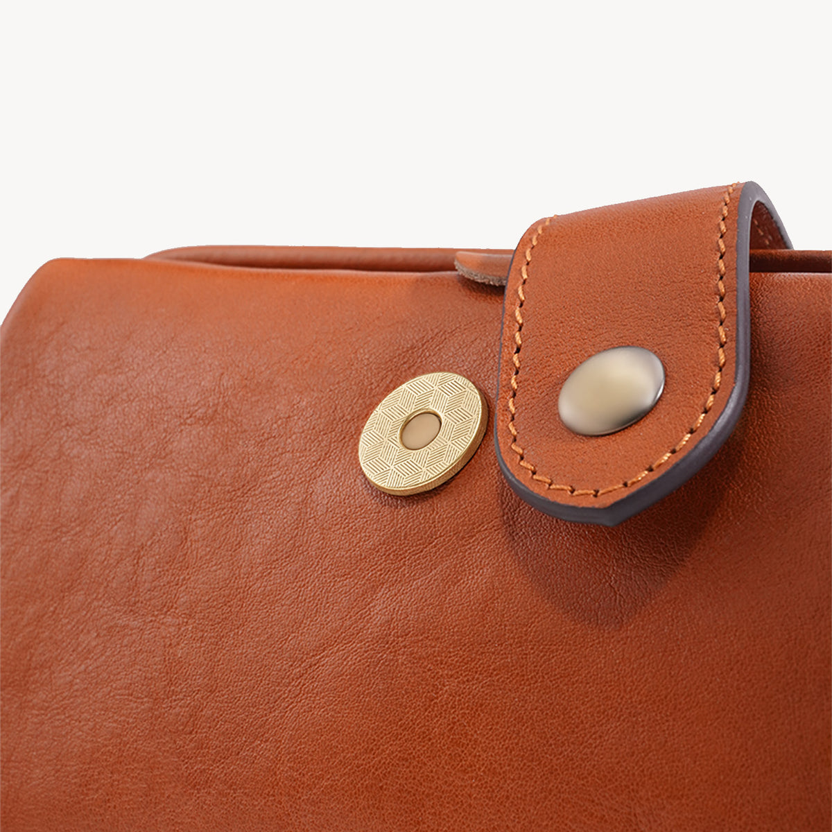 Leather closure tab and antique brass-tone snap detail