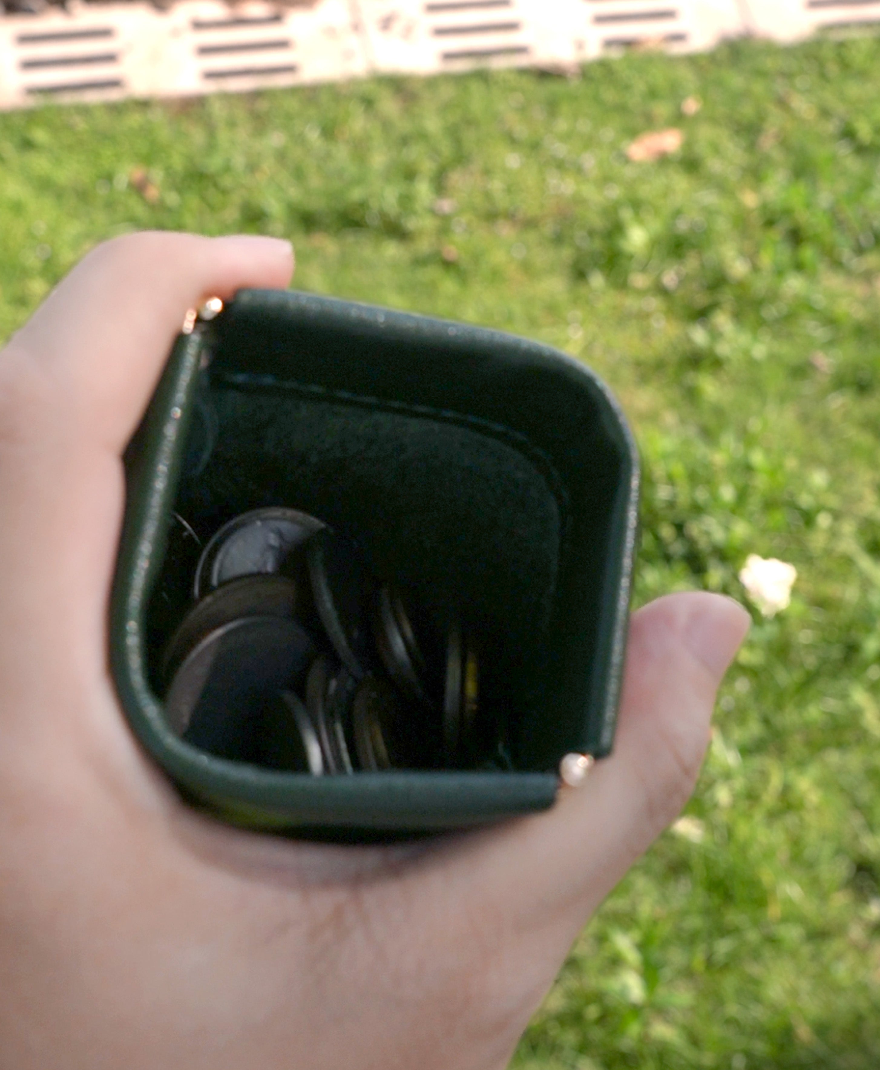 Green spring-top coin purse opened one-handed with coins inside