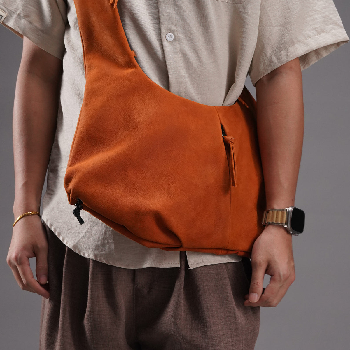 Orange cowhide utility crossbody bag worn close against the body