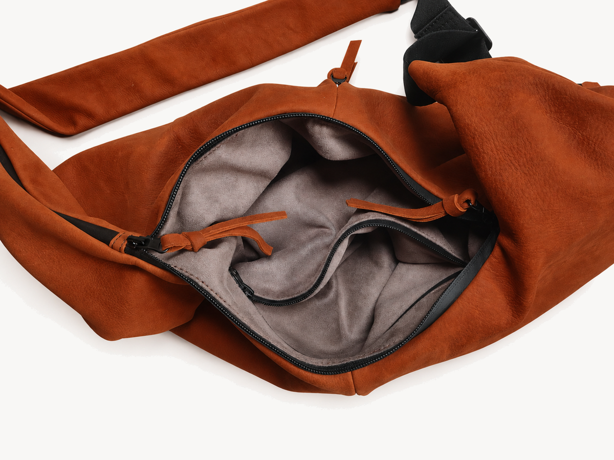 Open orange cowhide crossbody bag showing the lined interior and separate zip pocket