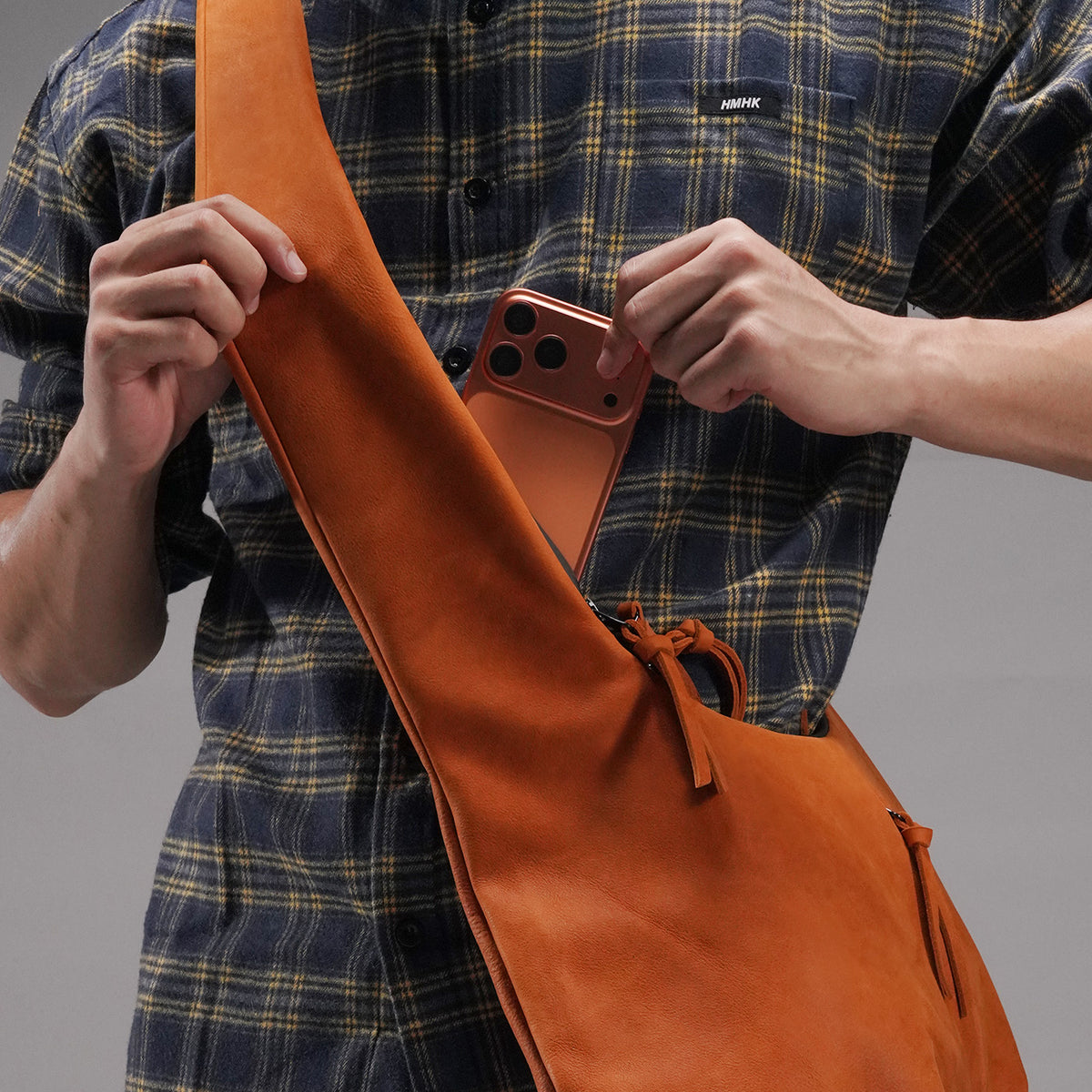 Phone being placed into the zippered pocket built into the wide shoulder strap